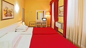 Habitación de hotel con dos camas, un escritorio con televisor, un espejo y una ventana con cortinas.
