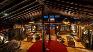 Interior de una cabaña de troncos con decoración rústica, muebles de madera y cuernos de ciervo.
