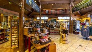 Una tienda bien iluminada con vigas de madera, estantes llenos de diversos productos y una zona de exhibición central.