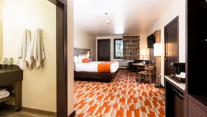 Habitación de hotel con cama, escritorio, silla, televisión y baño.