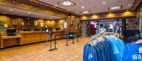 A hotel lobby with a reception desk, a clothing rack with blue shirts, and a stone wall in the background.