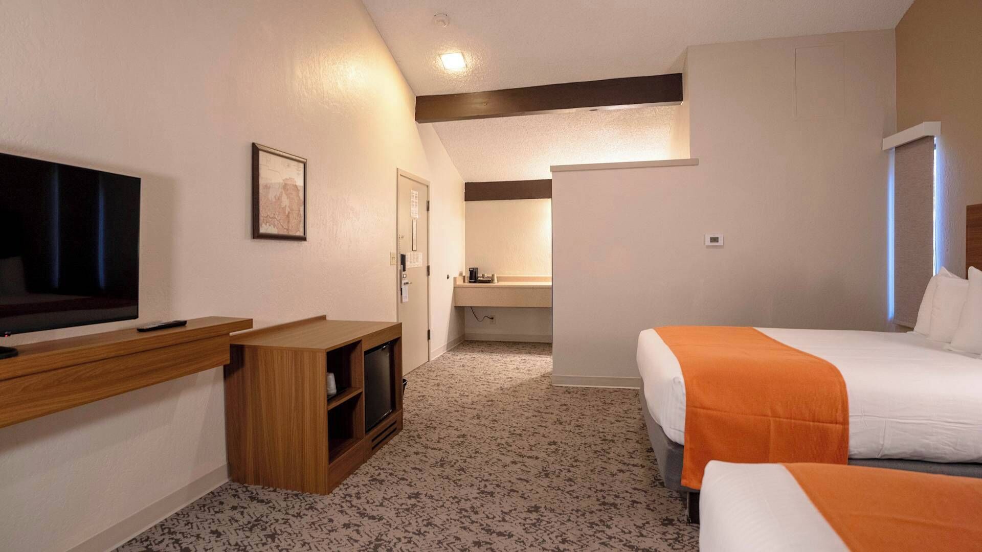 Una habitación de hotel con televisión, escritorio, cama y baño.