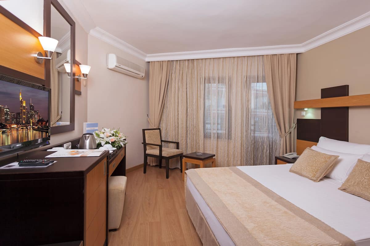Ein Hotelzimmer mit Bett, Schreibtisch, Stuhl und einem großen Spiegel.