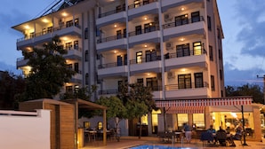 A multi-story hotel with a swimming pool and outdoor seating area.