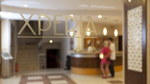 A blurred interior of a hotel with a reception desk and a sign that reads "XPERIA".