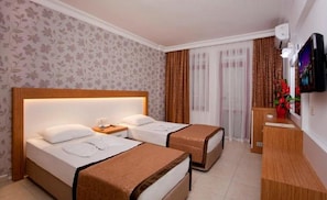 Habitación de hotel con dos camas, cabecero de madera, mesita de noche, televisor y ventana con cortinas.