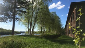 A grassy area with trees and a brick building. - Hotelli Ivalo (Inari)