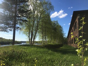 A grassy area with trees and a brick building. - Hotelli Ivalo (Inari)