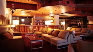 Un rincón lounge acogedor con sofás y una mesa de centro, techo de madera y una barra de fondo.