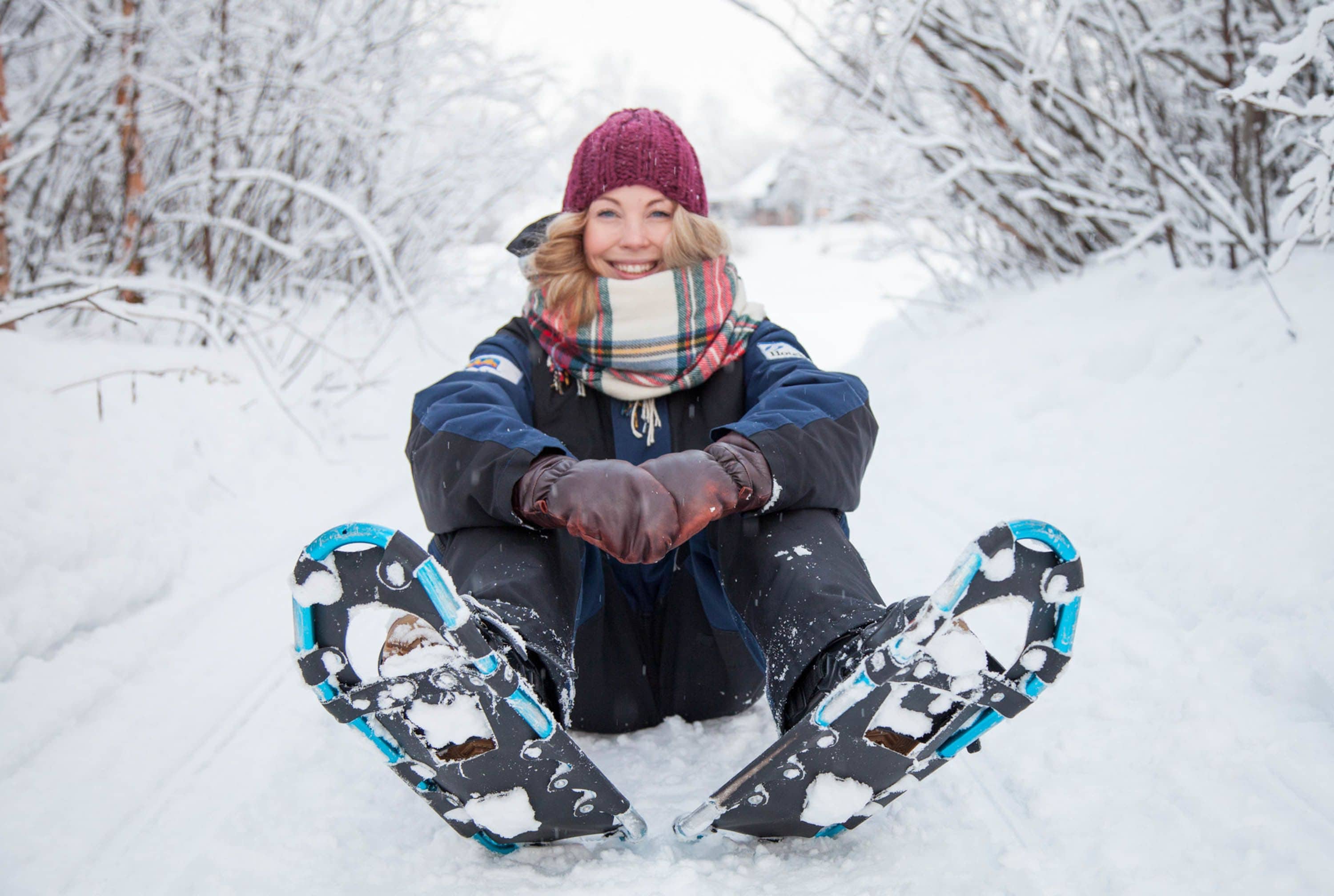 A person sitting in the snow with snow-covered trees in the background.