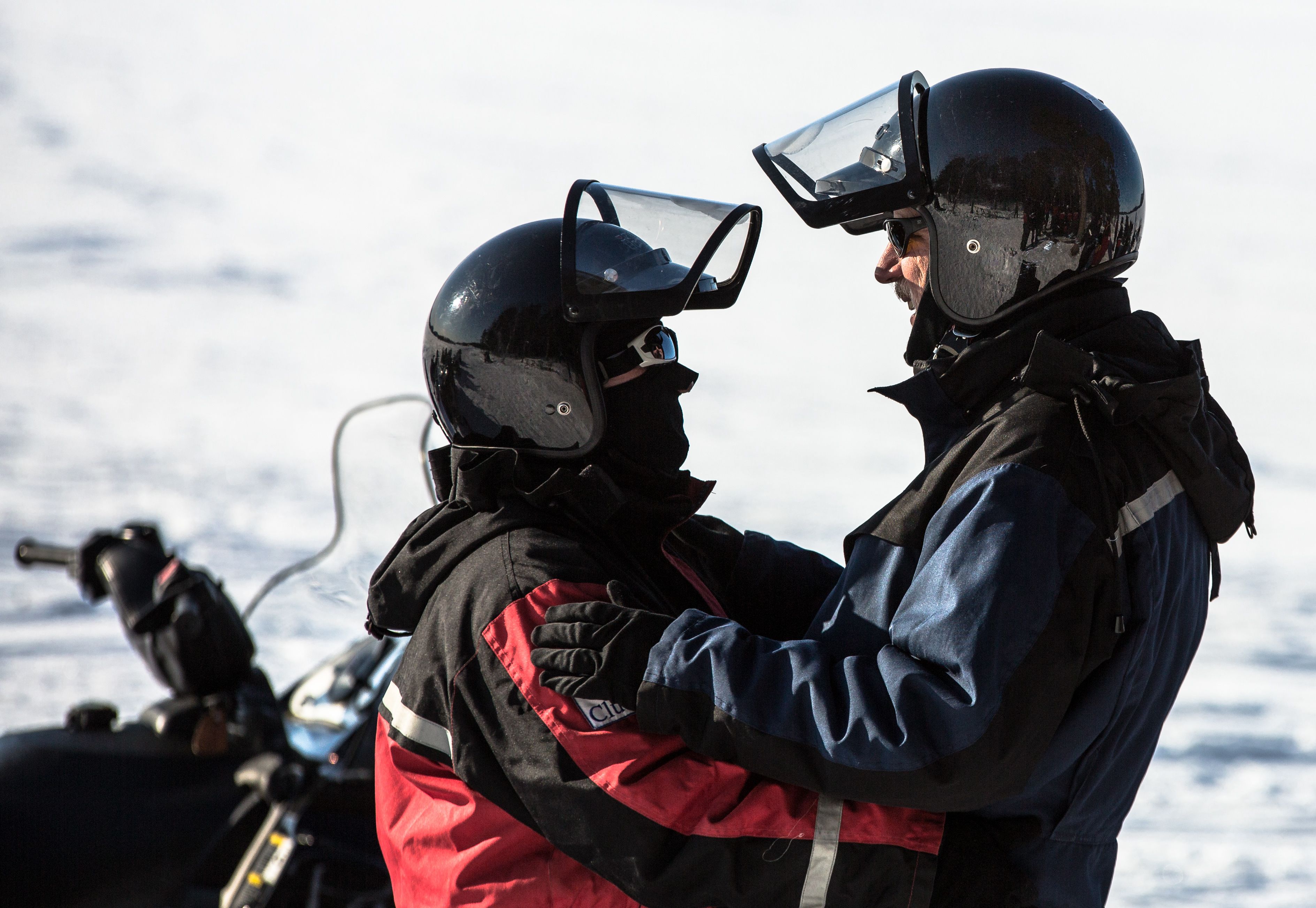 Two people on a motorcycle wearing helmets and jackets.