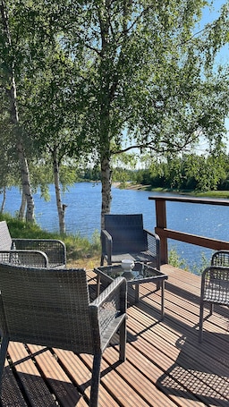 A wooden deck with wicker furniture and a view of a lake.