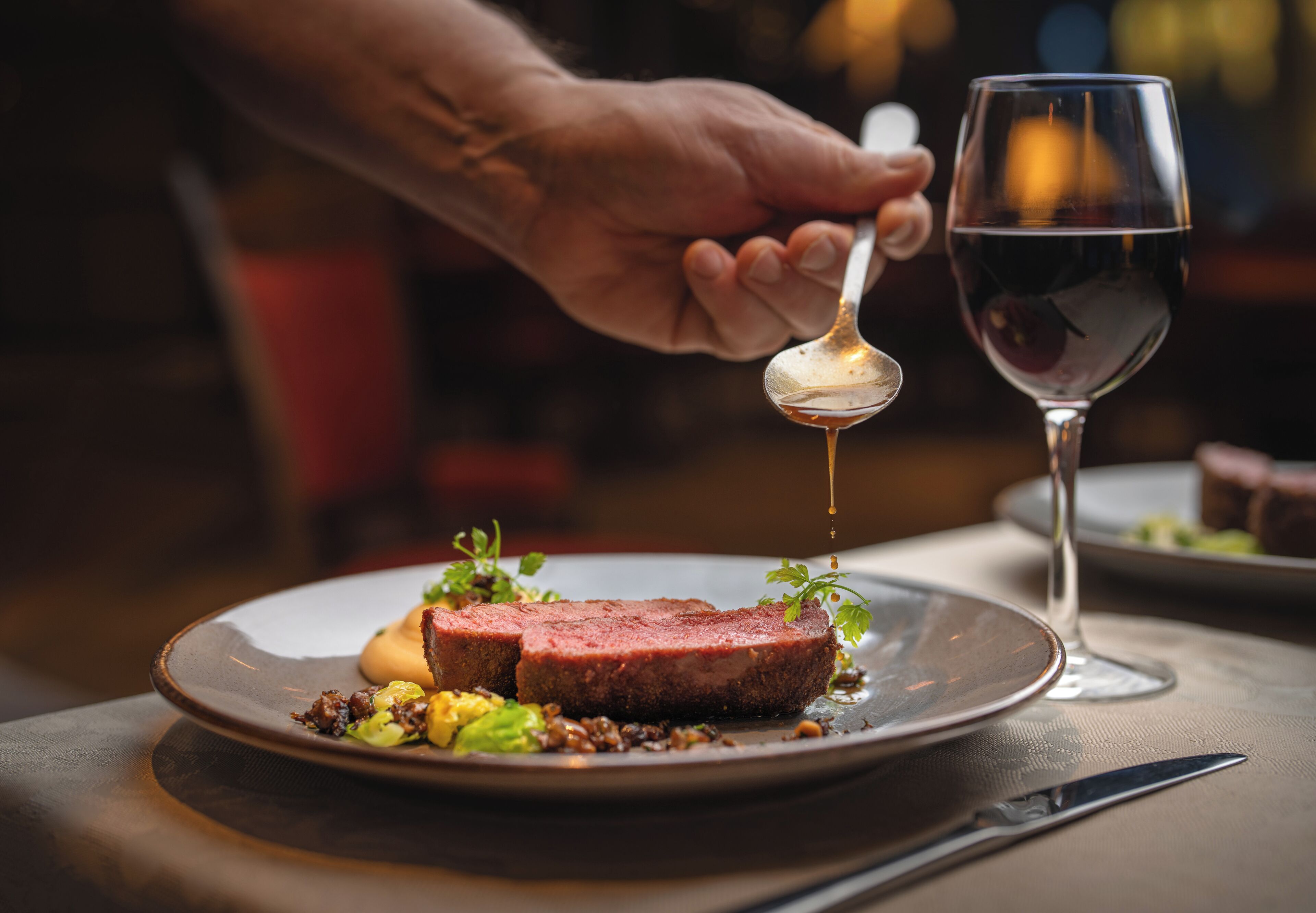 Une table à manger avec une assiette de nourriture, un verre d’eau et une cuillère.