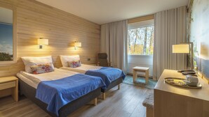 Habitación de hotel con dos camas, un escritorio, una silla y una ventana con cortinas.