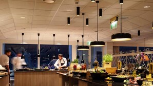 A modern kitchen with a central island, overhead pendant lighting, and a view of the city at night.