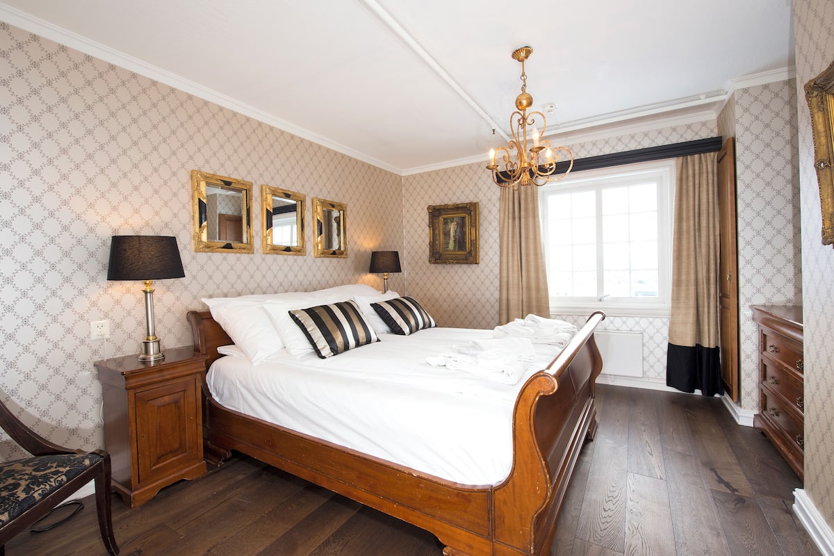 A classic bedroom with a wooden bed, two bedside lamps, and a chandelier.