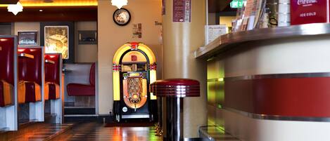 A hotel lobby with a checkered floor, a jukebox, and a Coca-Cola refrigerator.