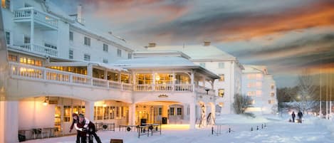 Een groot, meerijlaags hotel met een overdekt buitengebied en sneeuw op de grond.