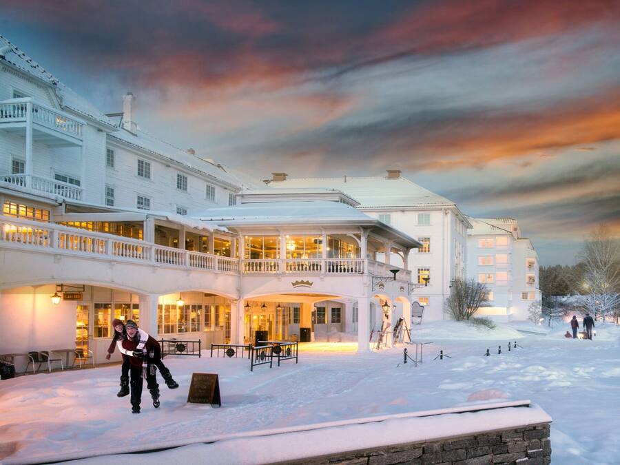 Un grand hôtel à plusieurs étages, doté d’un espace extérieur couvert et où la neige recouvre le sol.