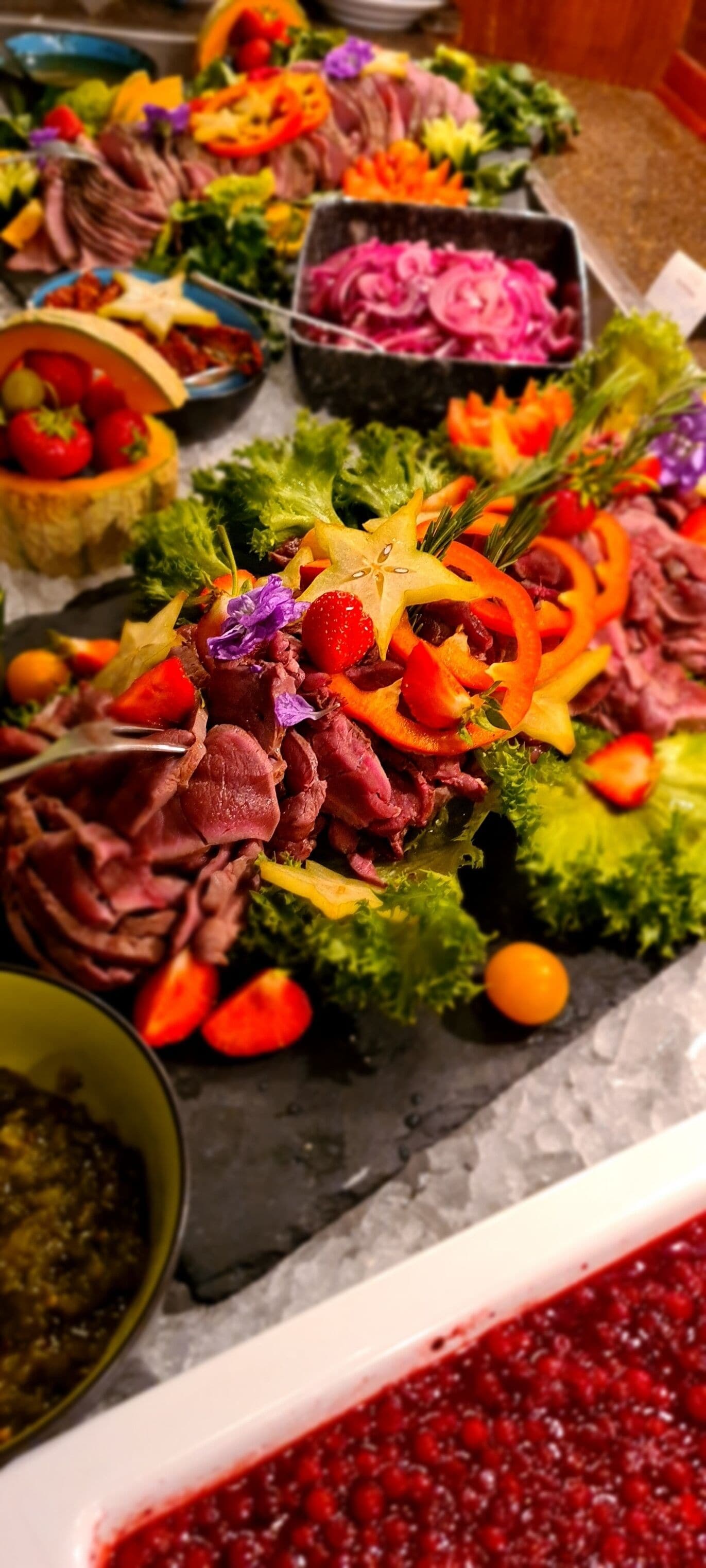 A buffet with various dishes including meat, vegetables, and fruits.