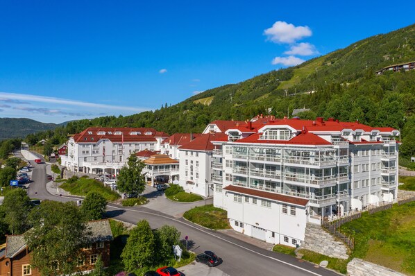 A large, multi-story hotel with a red roof, situated on a hillside with a view of the surrounding landscape.