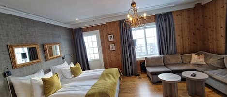 Een hotelkamer met een bed, twee slaapbanken, een bijzettafeltje en een kroonluchter.