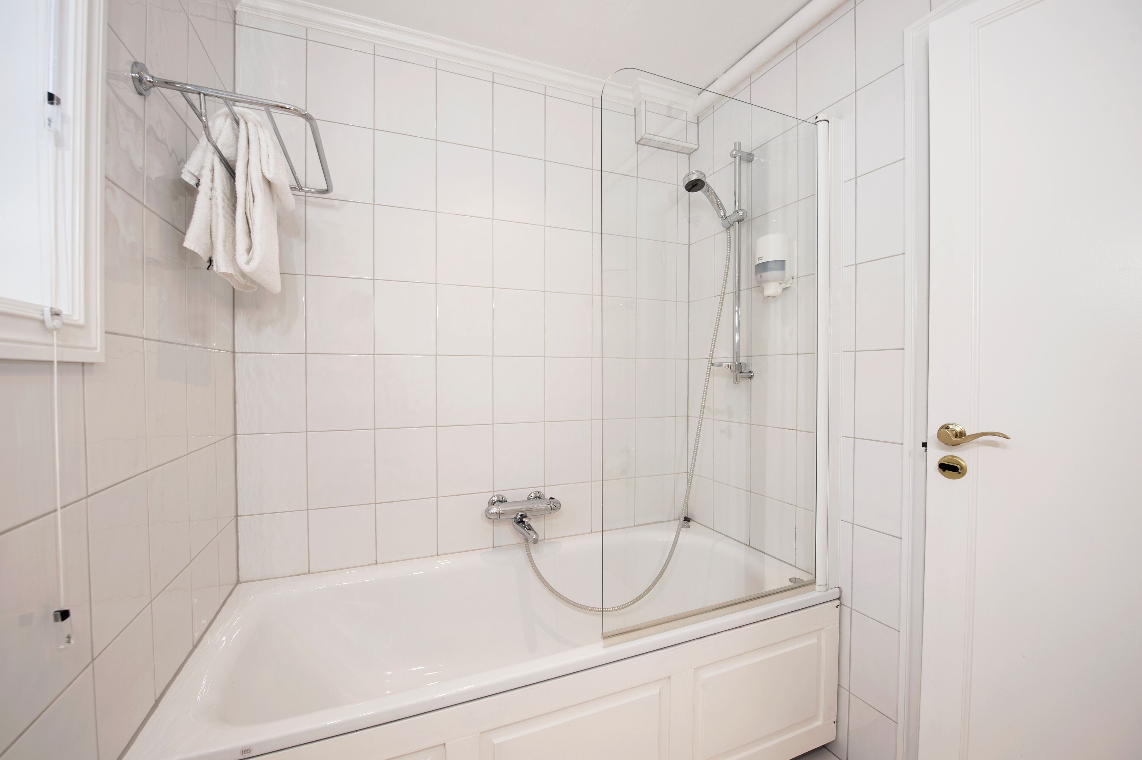 A modern bathroom with a glass-enclosed shower, a white bathtub, and a towel rack.