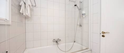 Un baño moderno con ducha acristalada, una bañera blanca y un perchero para toallas.