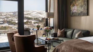 A hotel room with a sofa, a table with flowers, a lamp, and a painting. - Dr. Holms Hotel (Hol)