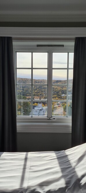 A room with a large window offering a view of a cityscape and hills.