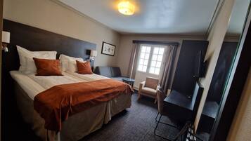 Een hotelkamer met een groot bed, een bureau, een stoel en een televisie.