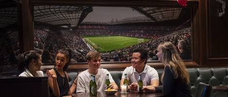 Un grupo de personas sentadas en una mesa de restaurante con vista a un estadio de fútbol.