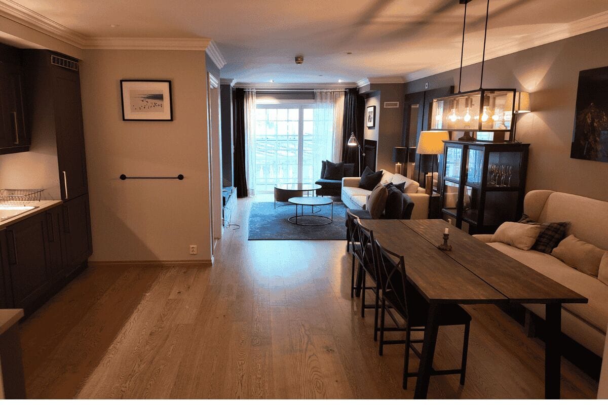 A modern living room with a dining area, a kitchen, and a large window.