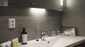 A modern bathroom with a white sink, a mirror, a towel rack, and toiletries.