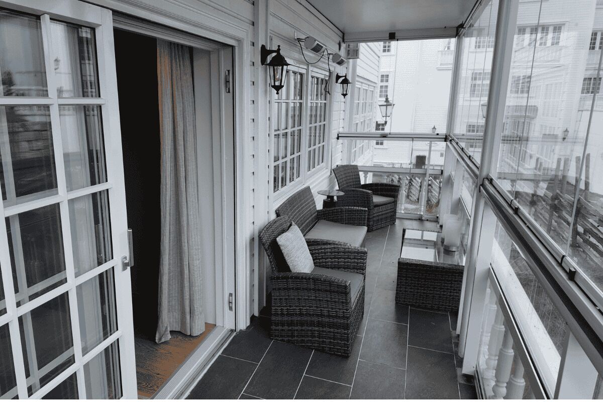 A balcony with wicker furniture, a glass door, and a view of buildings.