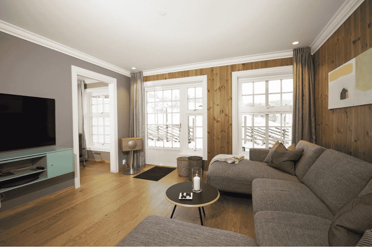 A living room with a sectional sofa, a television, and a large window with curtains.