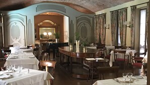 A restaurant with multiple tables set for dining, a brick archway, and a mirror reflecting the interior. - Albergo Le Due Corti (Como)