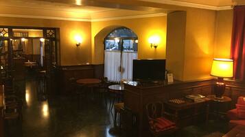 A hotel lobby with a reception desk, seating area, and a television.