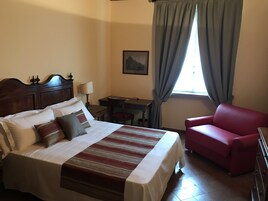 Un dormitorio ordenado con cama, escritorio y un sillón rojo.