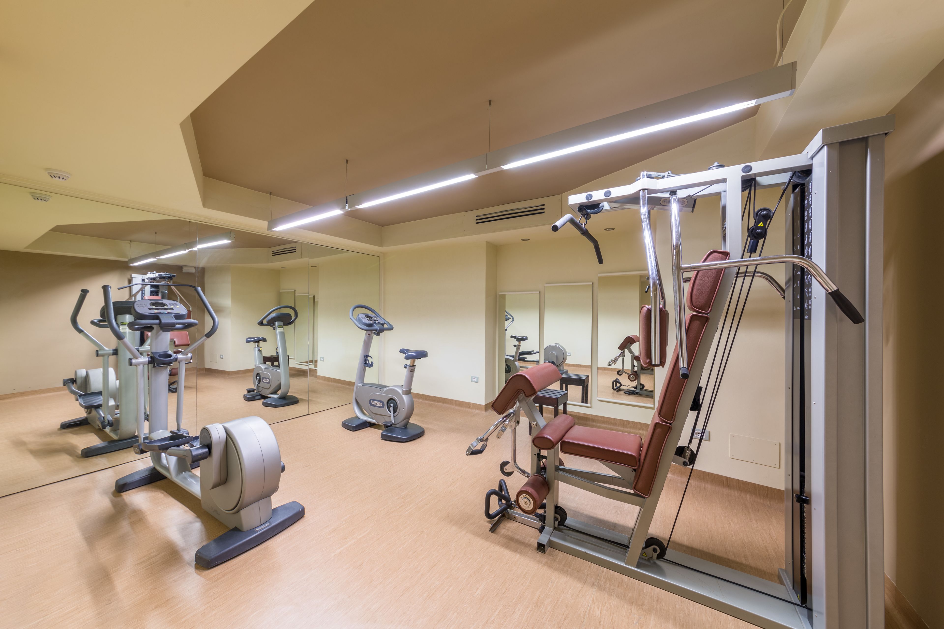 Ein Fitnessstudio mit verschiedenen Trainingsgeräten, darunter Laufbänder, Ergometer und Kraftgeräte.