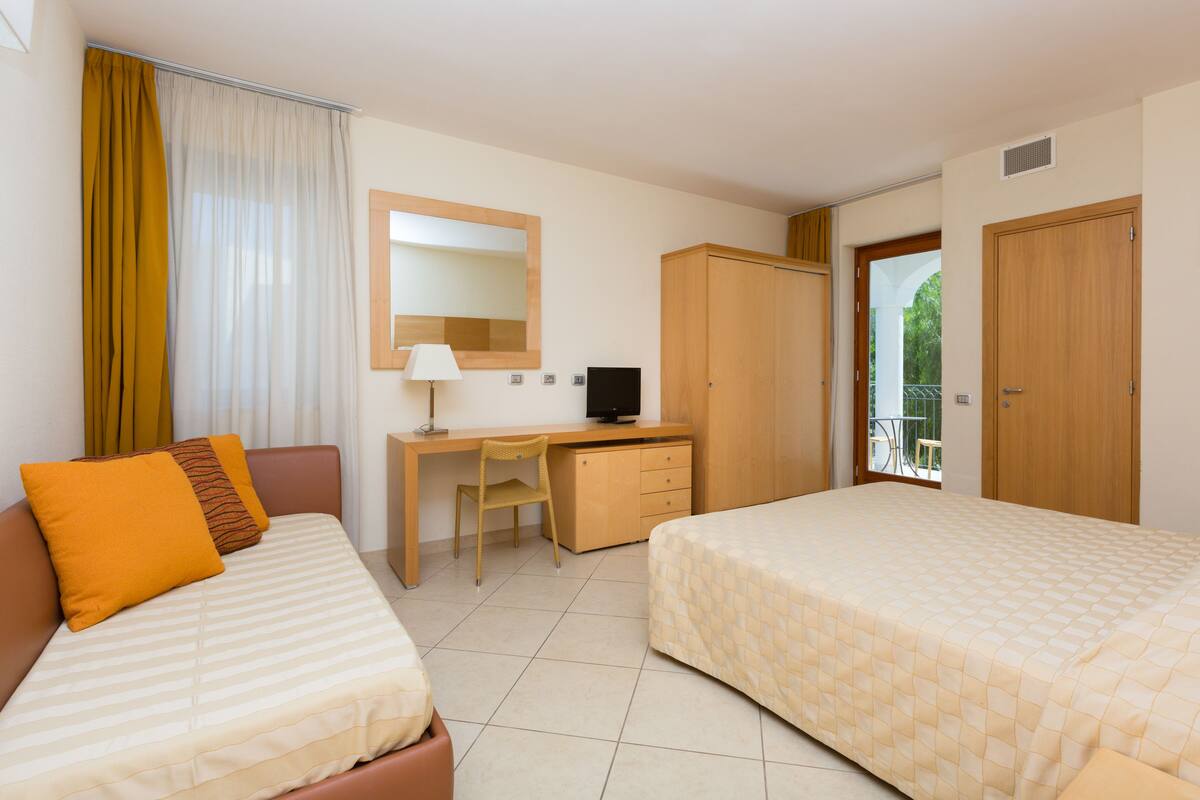 Habitación de hotel con dos camas, un escritorio, una silla, un televisor y un armario.