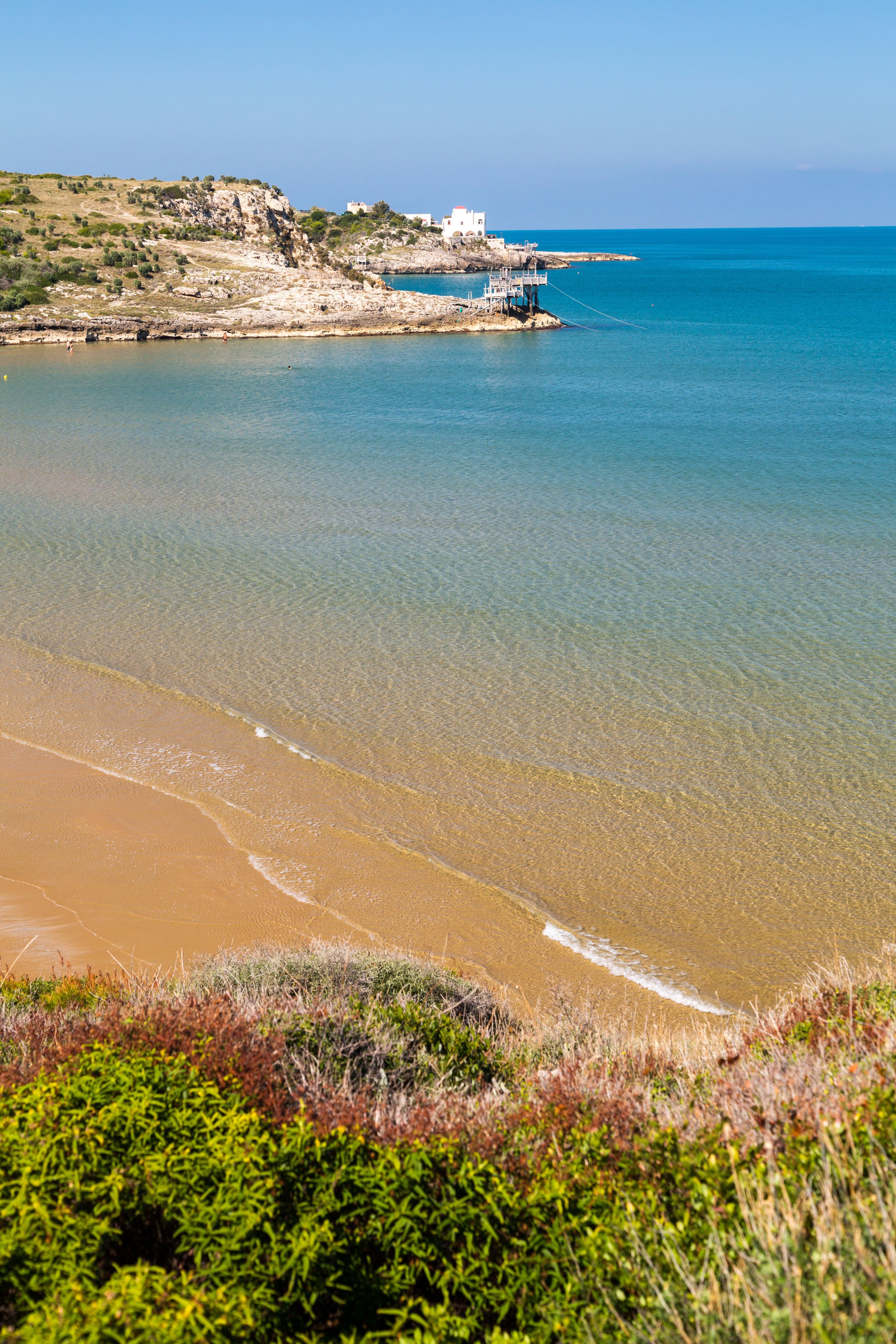 Un paisaje costero con vista despejada al mar, una playa de arena y terreno rocoso.