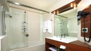 A modern bathroom with a glass-enclosed shower, a white toilet, and a wooden vanity with a mirror.