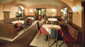 A restaurant with booths and tables, arched ceiling, and wall-mounted lights.