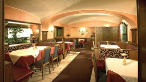 A restaurant with booths and tables, a tiled floor, and a warm color scheme. - Rokohof (Klagenfurt am Woerthersee)