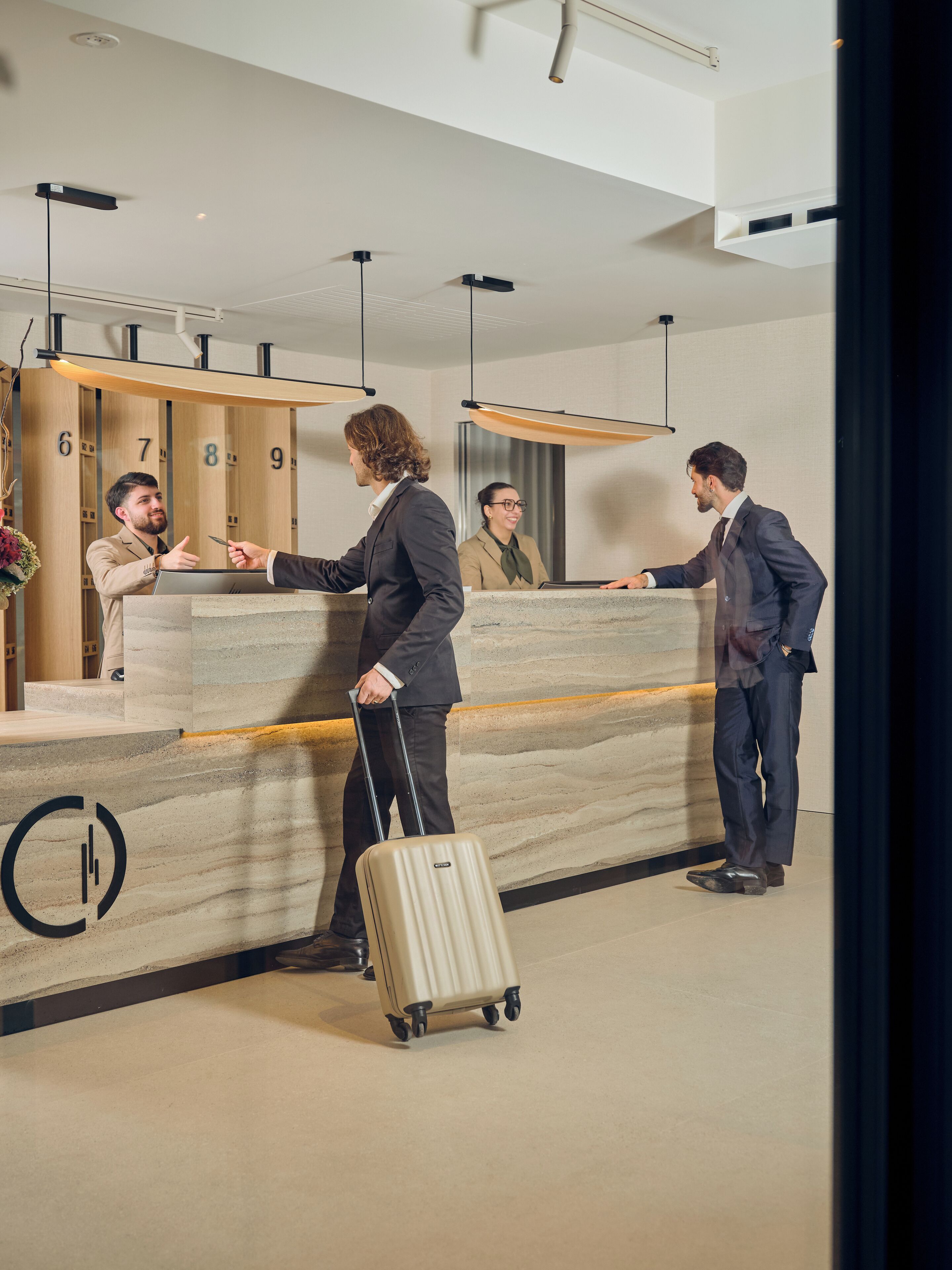 A hotel reception area with a marble counter, numbered guest rooms, and a modern ceiling design.