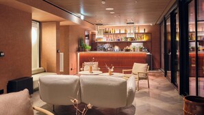 A modern bar area with a wooden ceiling, a bar counter with various bottles, and seating with a view of the bar. - IL LEON D'ORO HOTEL BARI – BY FARACE HOTELS (Bari)