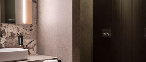 Une salle de bain moderne avec un lavabo en marbre, une serviette posée sur un porte-serviettes et un espace douche.