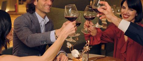 Un grupo de personas brindando con copas de vino alrededor de una mesa redonda en un restaurante.
