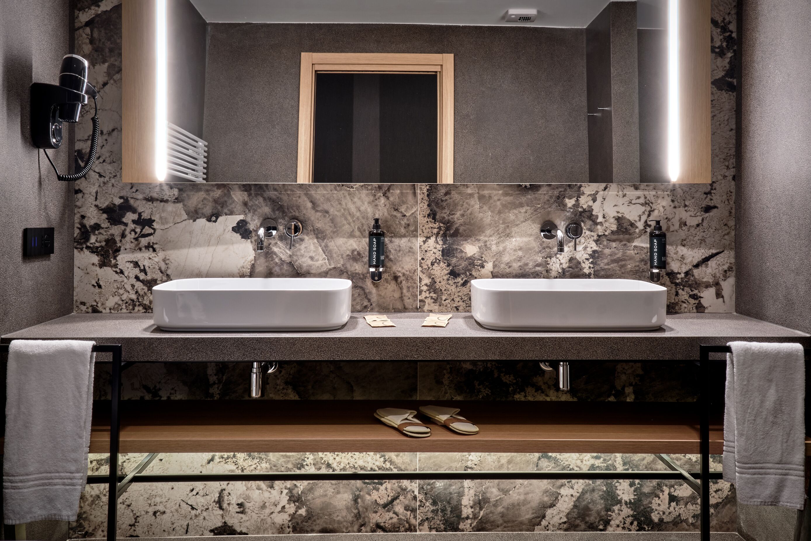 A bathroom with two white sinks, a large mirror, and a towel rack.
